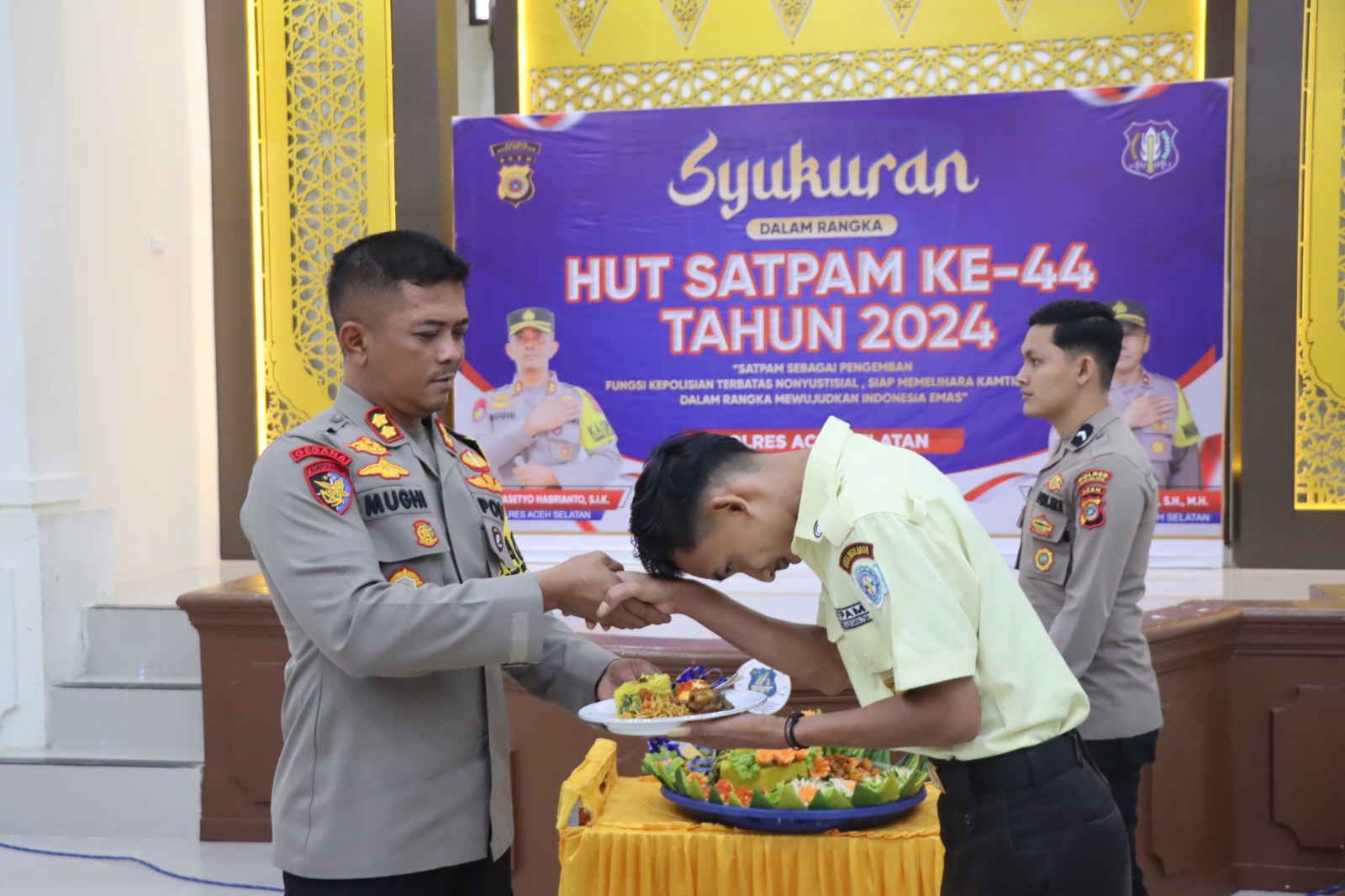 Kapolres Aceh Selatan AKBP Mughi Prasetyo Habrianto menyerah potongan kue HUT kepada personil Satpam termuda di Mapolres setempat, Rabu, (8/1).(poto/mediaaceh.co.id/istimewa)..